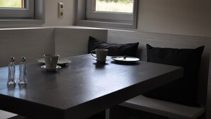 A dining area with a table, chairs, and a window with a view of greenery.