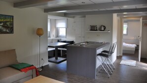 A modern kitchen with a central island, dining area, and a cozy seating space.