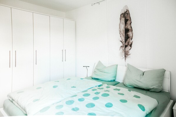 A bedroom with a bed, a wardrobe, and a feather decoration on the wall.