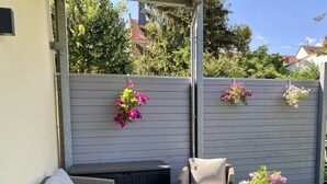 Une terrasse avec un canapé en osier, deux tables rondes et une chaise.