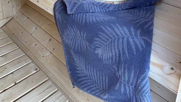 Un banc en bois pour sauna, avec un seau en bois et une louche posés dessus.
