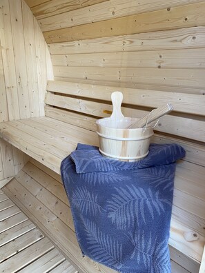 A wooden sauna bench with a wooden bucket and a ladle on it.