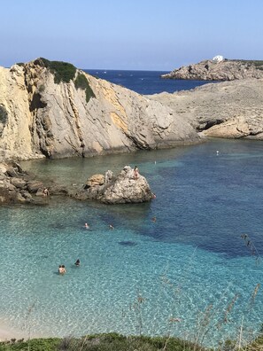 A coastal area with rocky cliffs and clear blue water. - Cozy apartment in Costa Arenal with sea views (Es Mercadal)