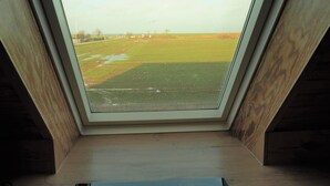 A skylight window with a view of a green field and a clear sky. - Family apartment with sea view (Fehmarn)