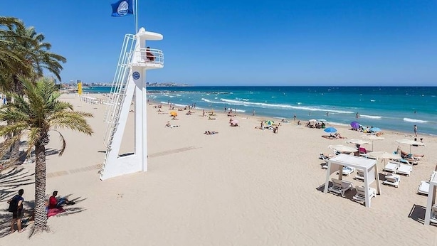 Een strand met een bewakerspost, parasols en ligbedden.