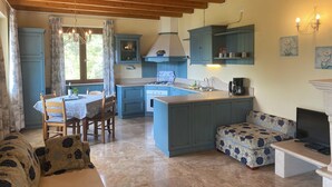 A cozy kitchen with blue cabinets, a dining table, and a sofa.
