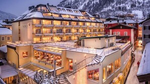 A hotel with multiple floors, balconies, and a view of snow-covered mountains. - Norica Hotel (Bad Hofgastein)