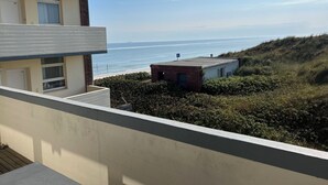 A balcony with a view of the sea and a building with a number '23' on the door. - Wooge Traum - With sea view directly on the beach (Wangerooge)