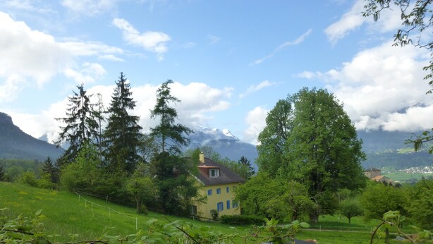 Une maison entourée d’une végétation luxuriante et de montagnes.