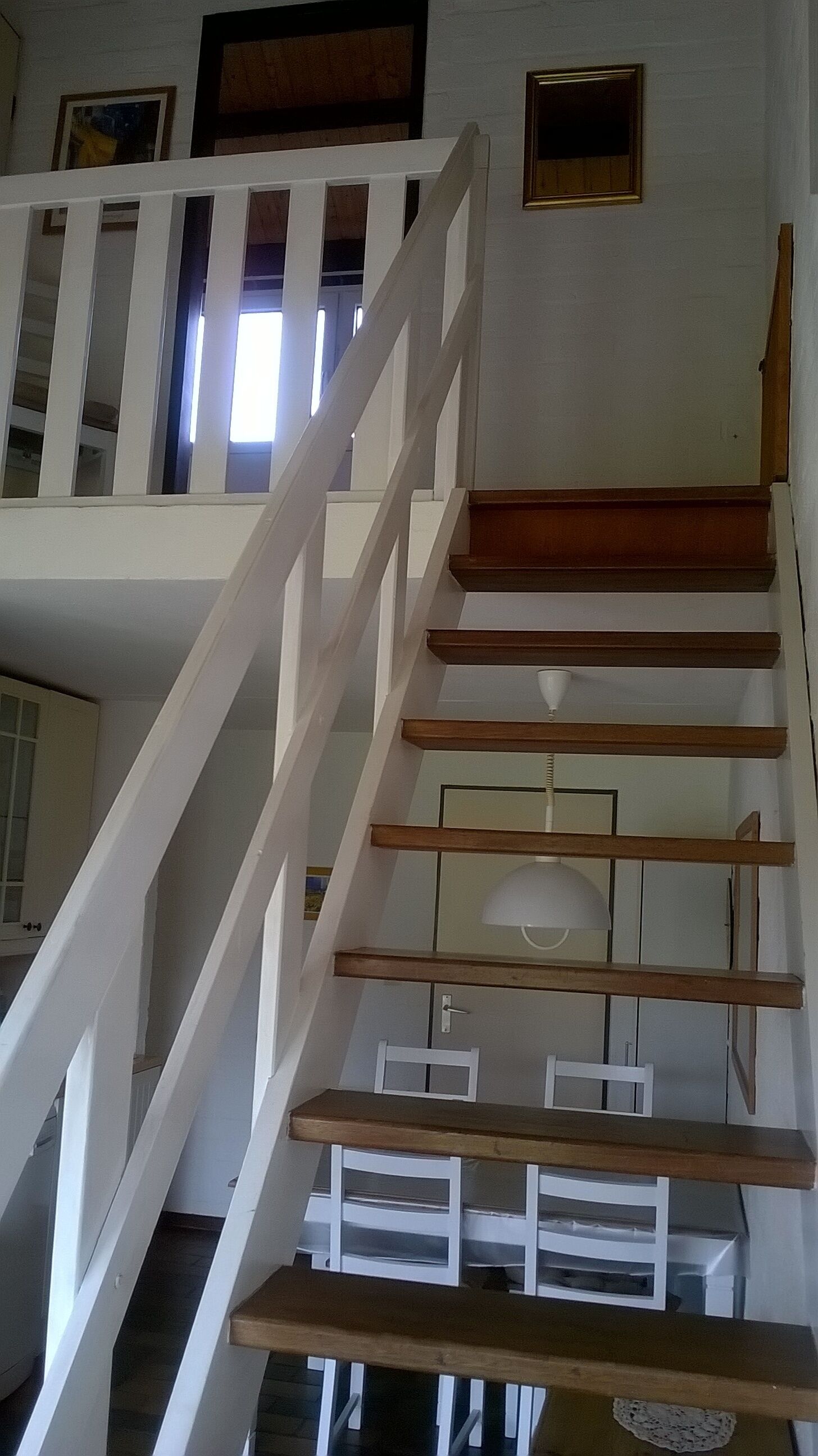 A staircase with white railings and wooden steps, leading to an upper floor.