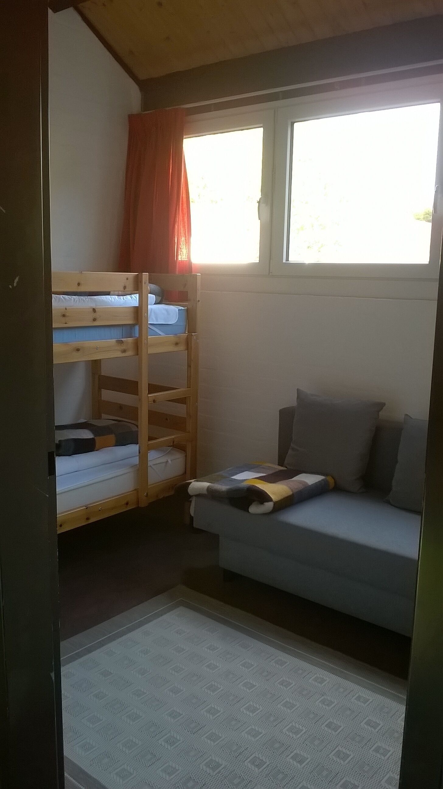 Une pièce avec un lit superposé, un canapé et une fenêtre.