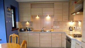 A compact kitchen with a wooden table and chairs, a built-in oven, and a sink.