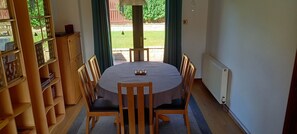 A dining area with a round table, wooden chairs, and a bookshelf.