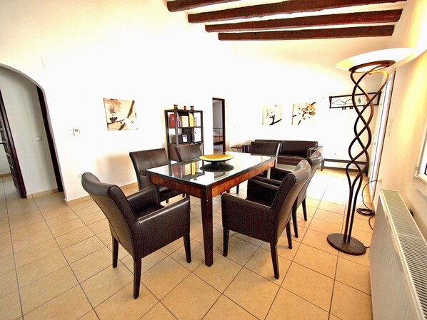 A dining area with a glass-top table surrounded by chairs, a bookshelf, and artwork on the walls. - Detached house with private pool, completely fenced, close to the beach (Denia)