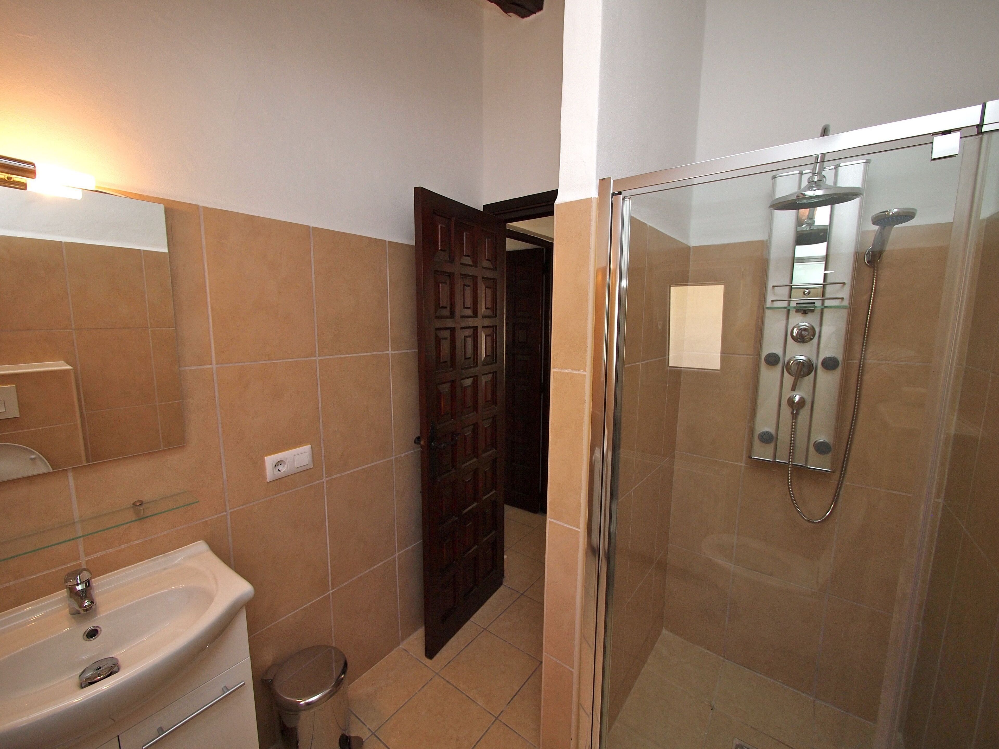 A bathroom with a sink, mirror, and shower.