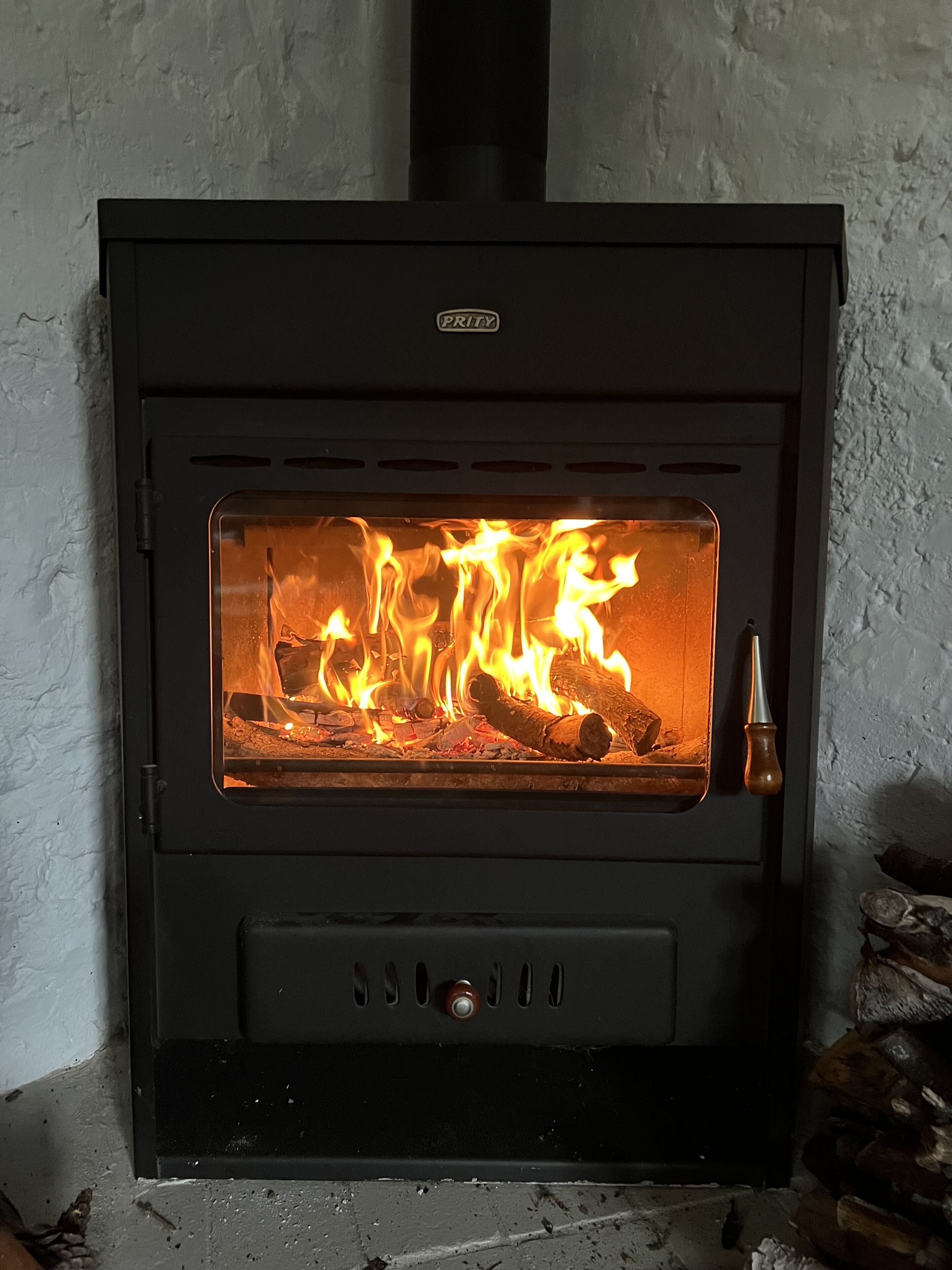A wood-burning stove with a glass front, a control panel below, and a chimney above.