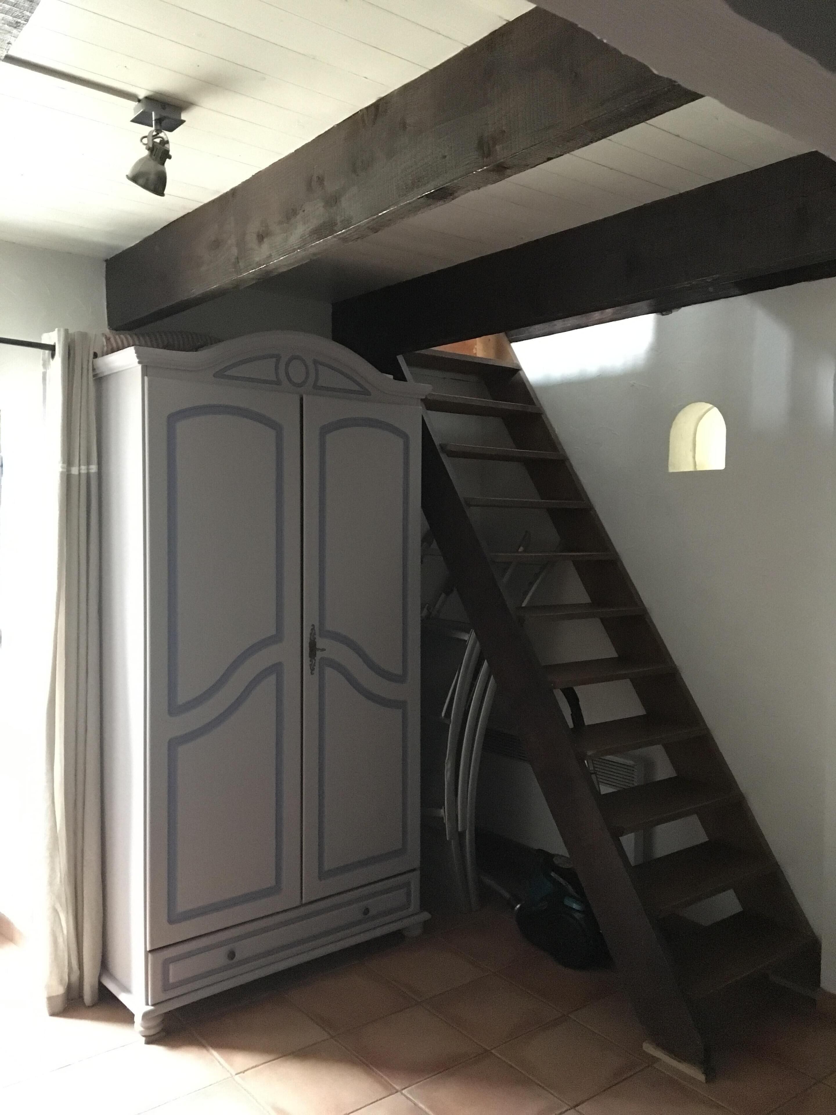 Ein Zimmer mit großem Kleiderschrank, einer Treppe und einem kleinen Fenster.
