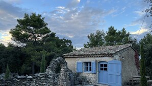 A rustic stone house with a tiled roof, a blue door, and a small porch area. - Charming, authentic cabanon all to yourself on almost 7000 m2 of land (Lacoste)