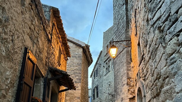 A narrow cobblestone street flanked by stone buildings with wooden shutters and a lantern. - Charming, authentic cabanon all to yourself on almost 7000 m2 of land (Lacoste)