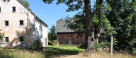 A rural setting with a stone building and a wooden barn.