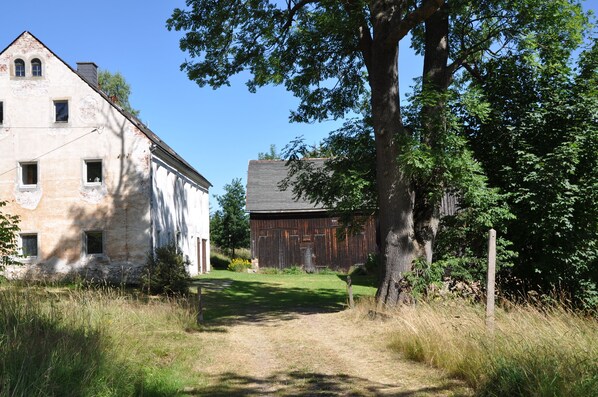 Un entorno rural con una construcción de piedra y un granero de madera.