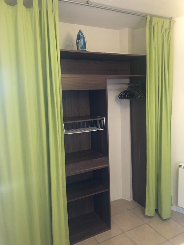 A room with a built-in wardrobe featuring multiple shelves and a hanging rack. - RENTAL CORSICA, T2, Haute-Corse, BALAGNE, CORBARA, 2 pers, Calm and rest assured (Corbara)