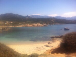 A coastal landscape with clear water, sandy beach, and distant mountains. - RENTAL CORSICA, T2, Haute-Corse, BALAGNE, CORBARA, 2 pers, Calm and rest assured (Corbara)