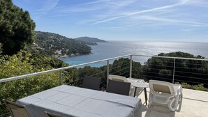 A terrace with a table and chairs overlooking a coastal view. - Beautiful sea view - Spacious and comfortable - Walking distance to the beach (Le Lavandou)
