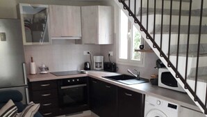 A compact kitchen with a washing machine, a dining table with chairs, and a staircase. - CORSE APARTMENT DUPLEX 6 PEOPLE  (Palasca)