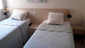 A bedroom with two single beds, a nightstand with a lamp, and a wall-mounted artwork. - CORSE APARTMENT DUPLEX 6 PEOPLE  (Palasca)