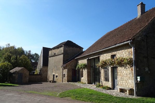 A traditional stone building with a courtyard, featuring a mix of stone and brick construction, and a sloped roof.