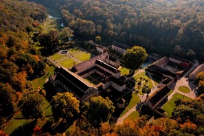An aerial view of a historic estate with multiple buildings, manicured gardens, and a river.