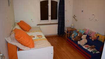Ein Schlafzimmer mit einem Bett, einem Fenster, einem kleinen Tisch und einer Couch mit Kuscheltieren.