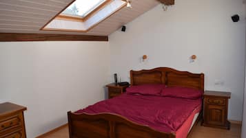Une chambre à coucher avec un puits de lumière, un lit en bois, des tables de chevet et une commode.