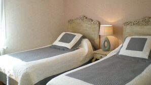 Twee eenpersoonsbedden met hoofdborden, een bedlampje, een hartvormige decoratie en een ingelijst schilderij aan de muur.