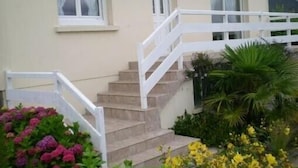 Een gebouw in beige tint met een witte trap die naar een deur leidt.