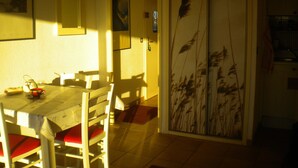 Un espace repas comprenant une table et des chaises, une porte ornée d’un panneau décoratif et un mur où sont accrochées des œuvres d’art encadrées.