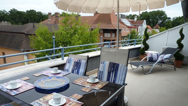 Eine Terrasse im Freien mit Tisch für zwei Personen, ausgestattet mit gestreiften Kissen und einem dekorativen Teller.