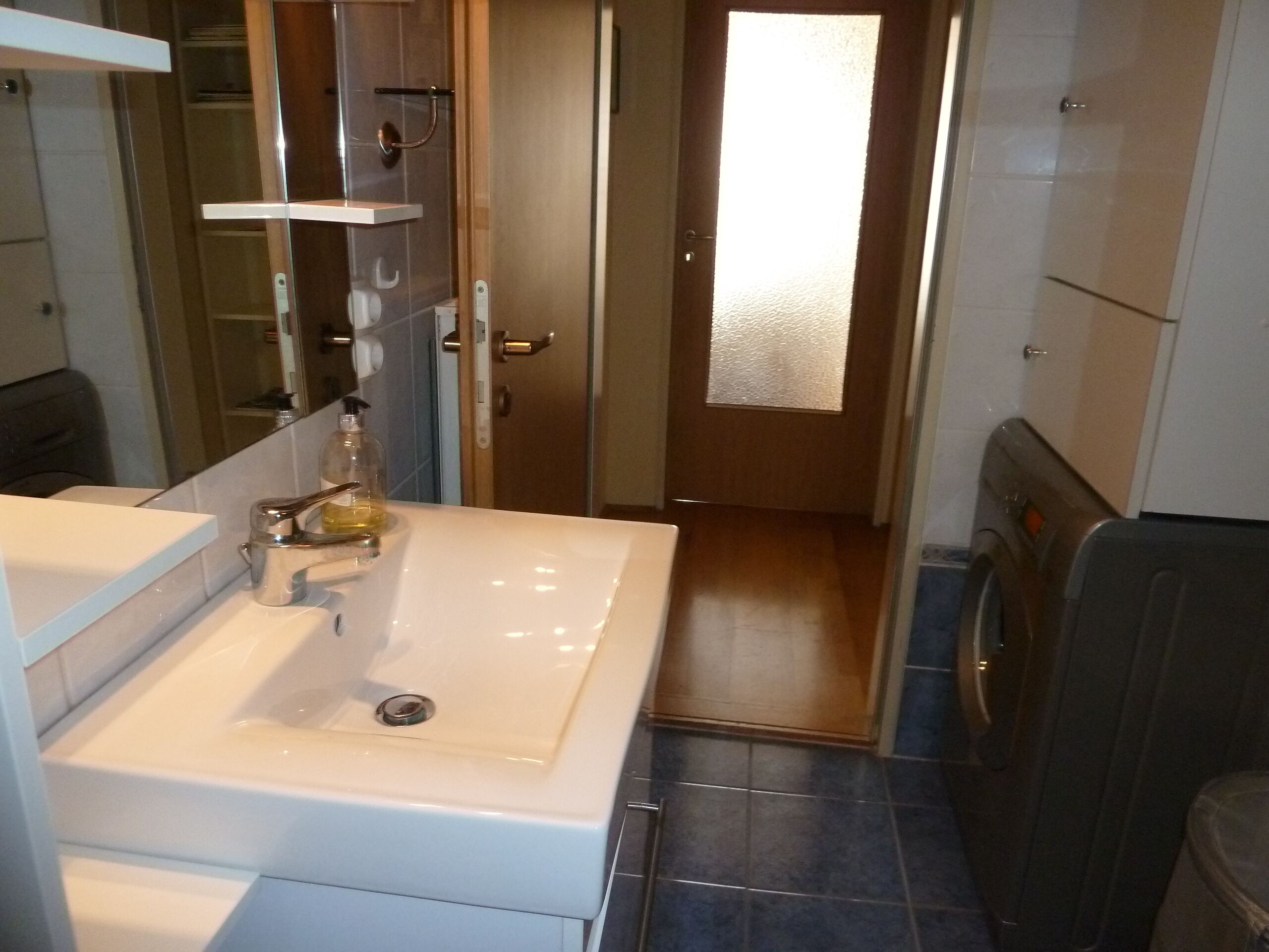 Une salle de bain avec un lavabo blanc, un miroir, un porte-serviettes et un espace douche.