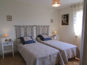 Un lit double avec une tête de lit, deux tables de chevet, une lampe et un tableau au mur.