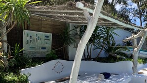 Eine Holzterrasse mit einer weißen Bank, einer Hängematte und einer rustikalen Wand mit einem Schild.