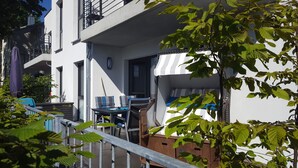 Een balkon met buitenmeubilair, een houten kist en uitzicht op de gevel.