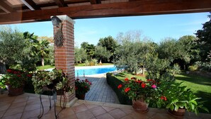 A covered patio with a view of a swimming pool, surrounded by potted plants and a brick pillar. - Dream villa with large swimming pool, 800m from the sea with 5 bedrooms 4 bathrooms (Porec)