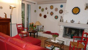 Un salon avec un canapé rouge, une cheminée et des œuvres d’art décoratives au mur.