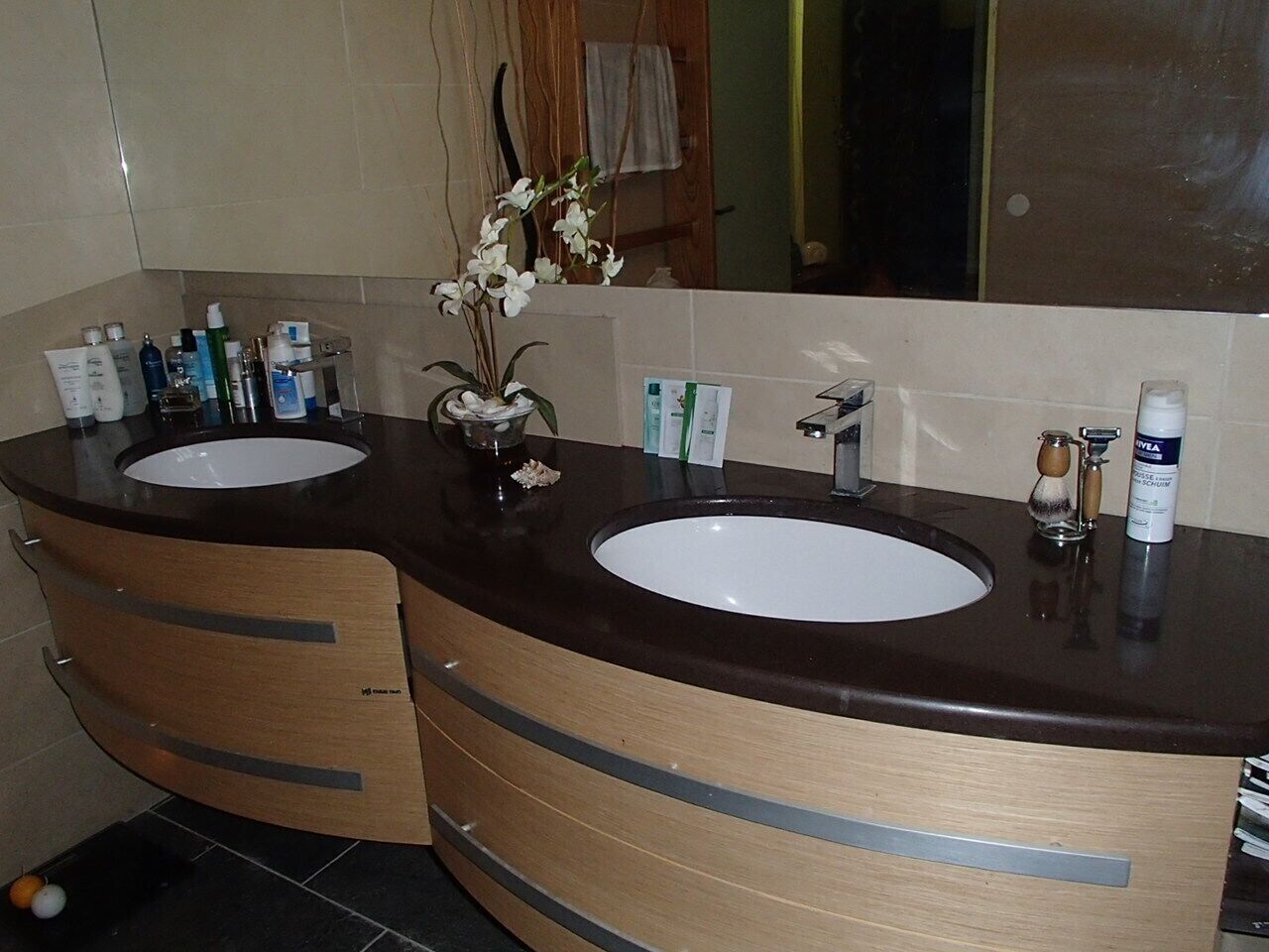 Ein Badezimmer mit zwei Waschbecken, einem Spiegel und Toilettenartikeln.