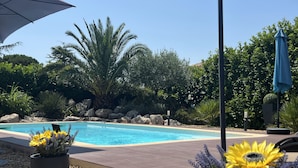 A swimming pool surrounded by rocks and plants, with a clear blue sky above. - MODERNITY, COMFORT, SWIMMING POOL, VIEW AT THE FOOT OF MONT VENTOUX (Modène)