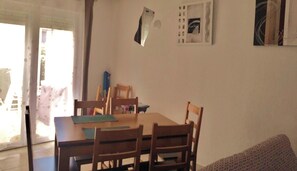 A dining area with a table and chairs, a ceiling fan, and a door leading to a garden.