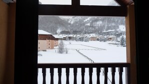 Une vue sur une montagne enneigée, prise depuis un balcon doté d’une balustrade en bois.