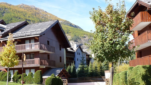 Un hôtel doté de nombreux balcons, situé au pied d’une montagne et disposant d’un parking.