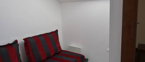 Una habitación pequeña con cama individual, techo inclinado y tragaluz.